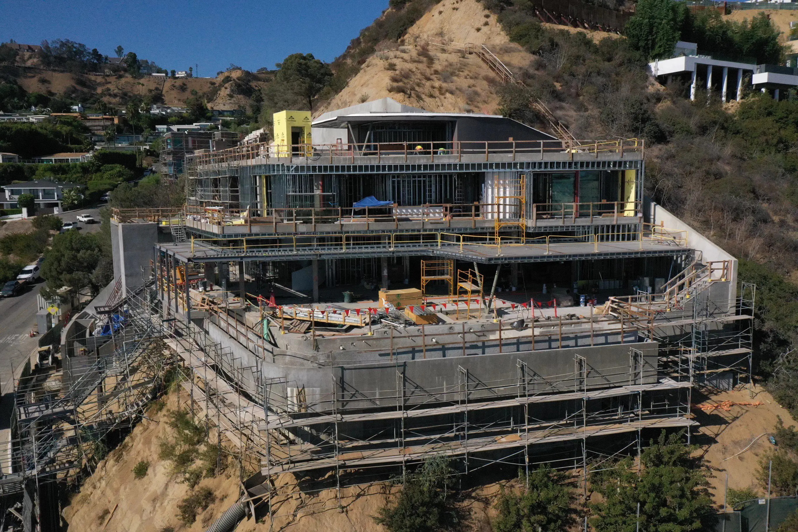 Modern hillside mansion under construction with scaffolding
