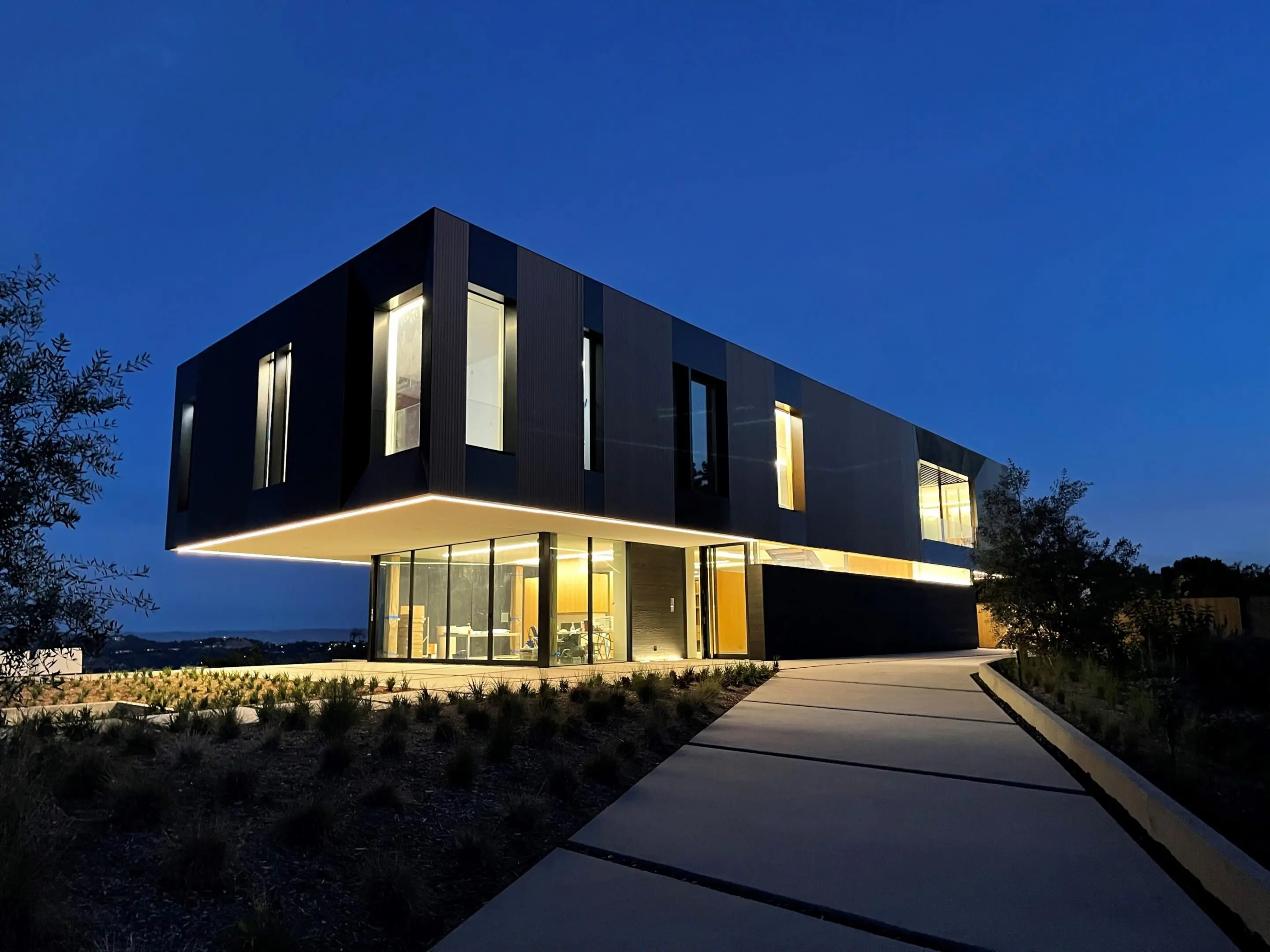Modern cantilevered house at dusk with driveway