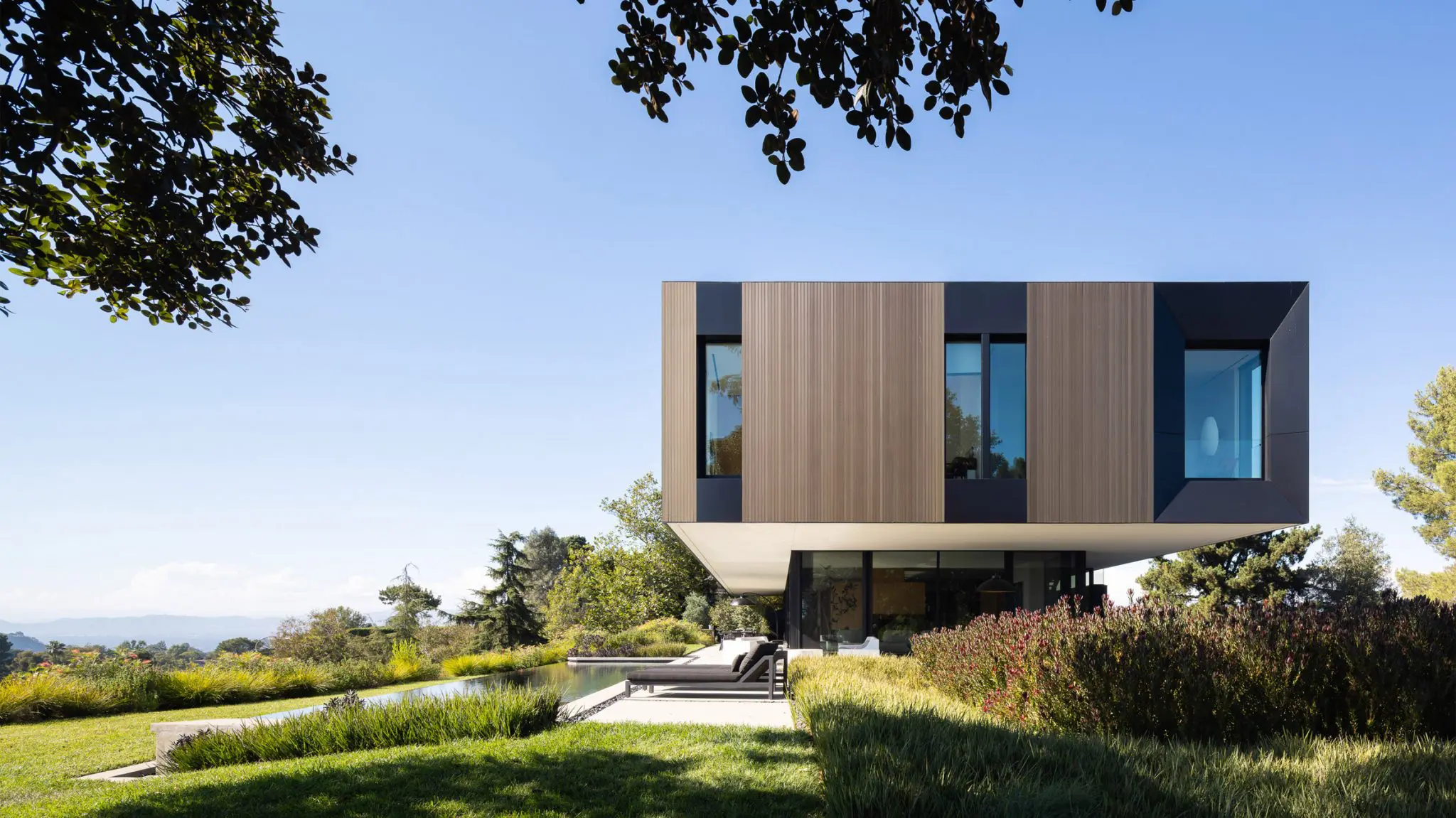 Modern cantilevered glass house in landscaped setting